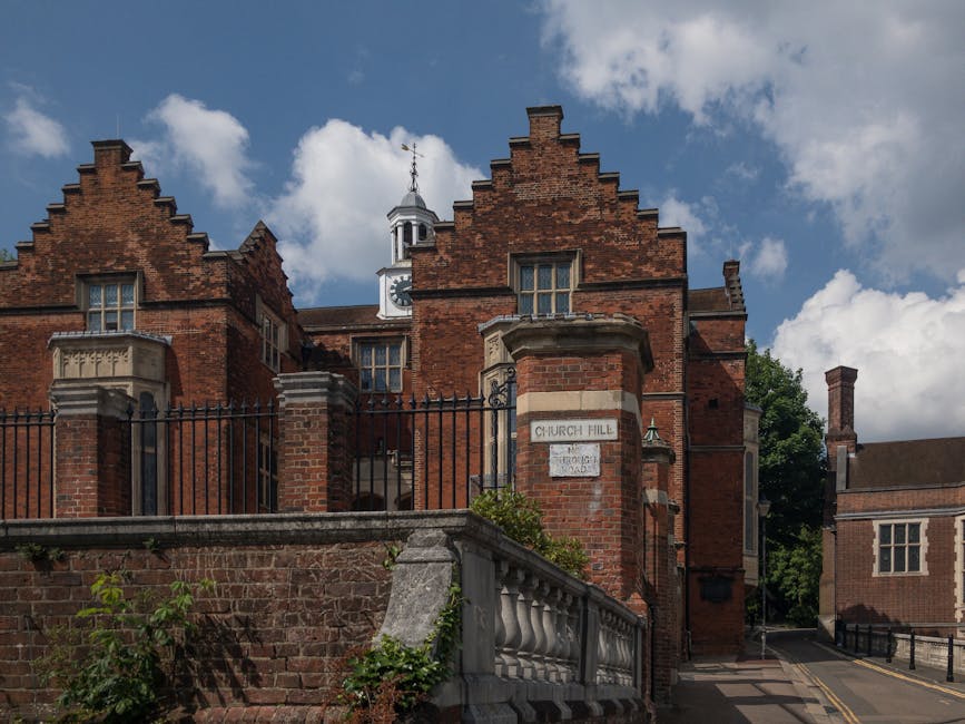 A historic red-brick building with a stepped gable roofline and multiple windows, located on Church Hill in Harrow Weald, viewed from a street with a stone retaining wall and iron fence in the foregro
